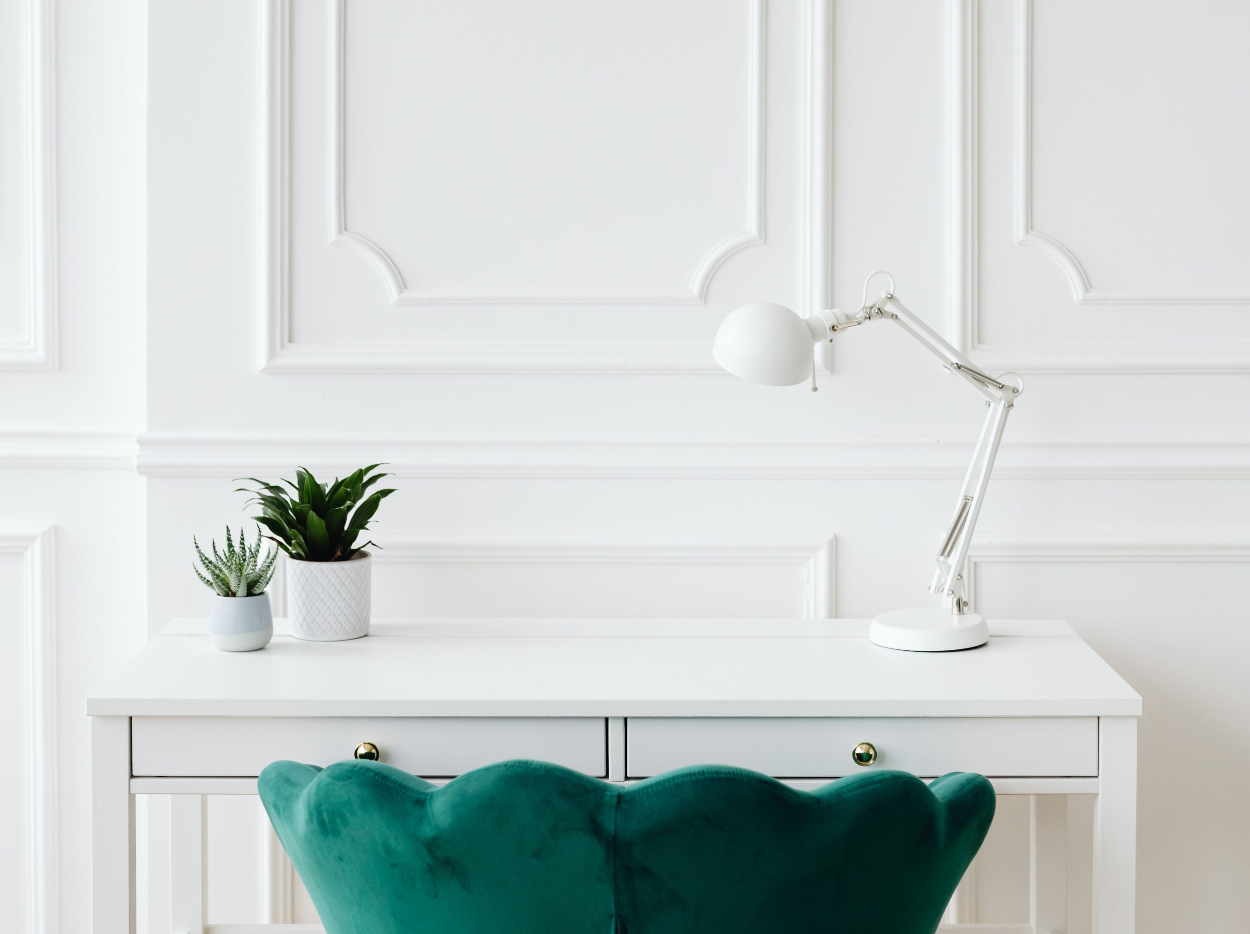 home office with lamp desk plants and green velvet chair