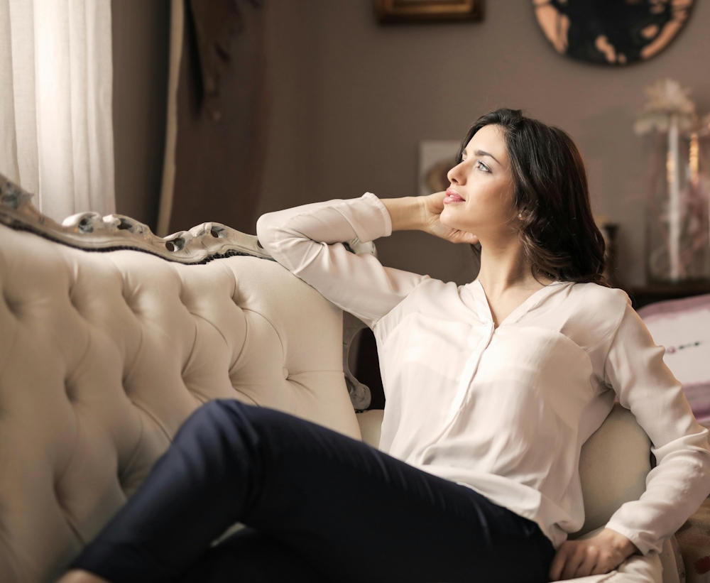 Woman reclining on luxurious couch gazing out of the window